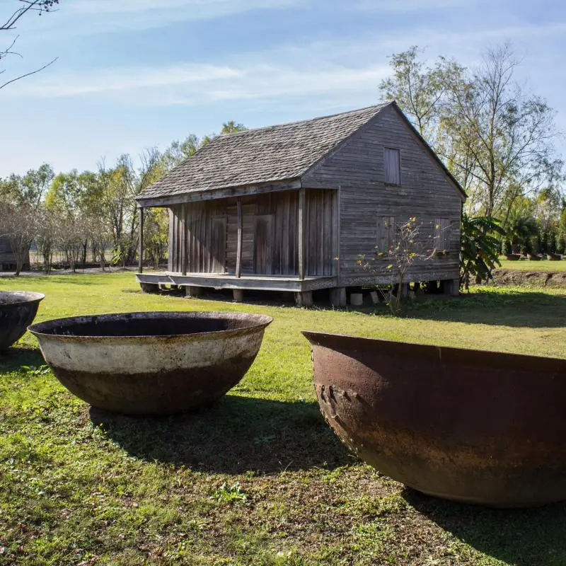A few large bowls and an old cabin at the Whitney plantation during a Whitney plantation tour